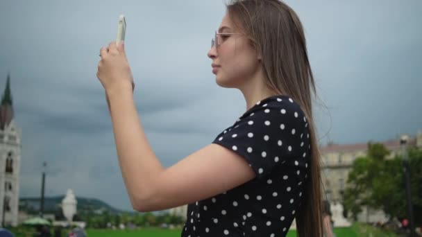 Κορίτσι λήψη φωτογραφιών smartphone του ουγγρικού Κοινοβουλίου Κτίριο στη Βουδαπέστη - Πλάνα, βίντεο