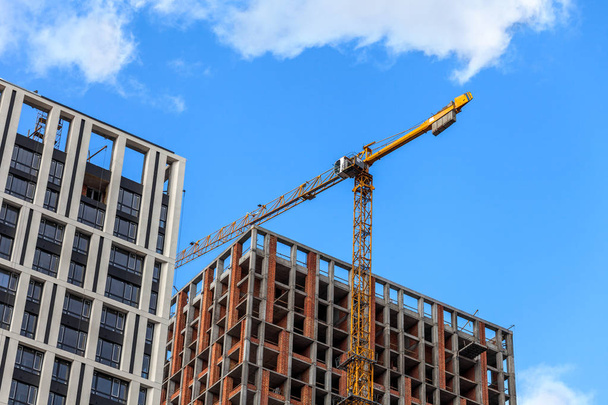 Construction of a modern residential complex. The construction of a multi-story building. cargo crane on a background of blue sky. - Photo, Image