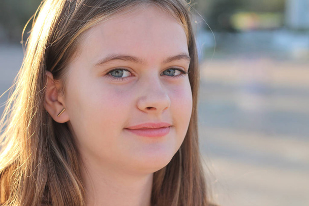 Портрет милой белой девушки-подростка на размытом фоне летнего зеленого города
 - Фото, изображение
