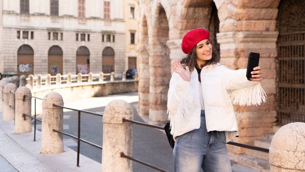 Elegant woman tourist taking a photo in front of the amphitheater, antiquity, europe - 写真・画像