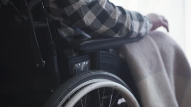 障害者の白人男性が座っている車椅子のクローズアップ。動きのための装置を使用して成熟した麻痺した男。障害、高齢、ライフスタイル. - 映像、動画