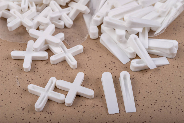 White plastic clinics and crosses for laying ceramic tiles. Accessories and tools necessary for construction workers. Light background. - Photo, Image