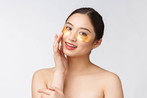Азиатская красотка-подросток ухаживает за своей кожей с золотыми масками под глазами
 - Фото, изображение