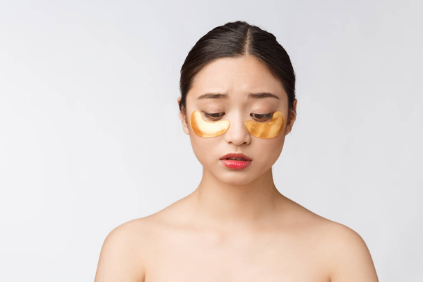 Asian beauty teenager woman care her skin with gold eye masks patches under eyes with worry. - Fotoğraf, Görsel