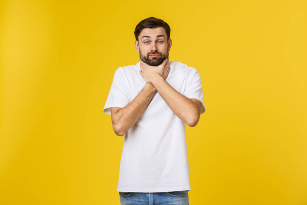 Ανησυχημένος νεαρός άνδρας στέκεται απομονωμένος στον κίτρινο τοίχο - Φωτογραφία, εικόνα