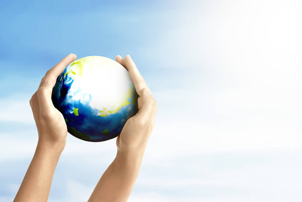 Human hands holding the earth with a blue sky background. Earth day concept - Fotoğraf, Görsel