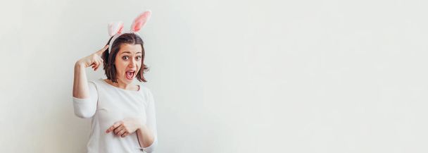 Fijne Paasvakantie viering voorjaar concept. Jonge vrouw met konijnenoren geïsoleerd op witte achtergrond. Voorbereiding van de vakantie. Meisje dat er gelukkig en opgewonden uitziet, die plezier heeft op Paasdag. Banner - Foto, afbeelding