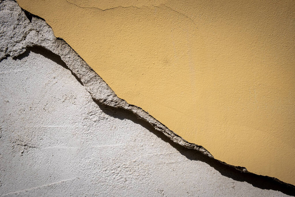 Παλιό ραγισμένο και επικίνδυνο καταρρέει κίτρινο τοίχο ενός εγκαταλελειμμένου σπιτιού - Φωτογραφία, εικόνα