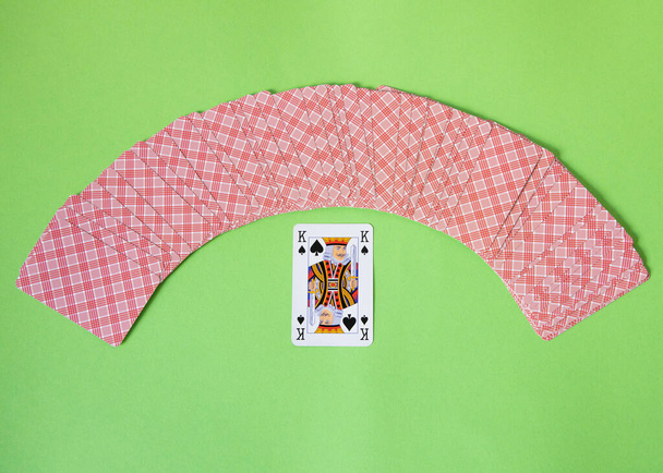 Τυχαίες κάρτες πόκερ σε μορφή Arc πάνω από ένα πράσινο φόντο με μια προεδρική κάρτα βασιλιά. - Φωτογραφία, εικόνα