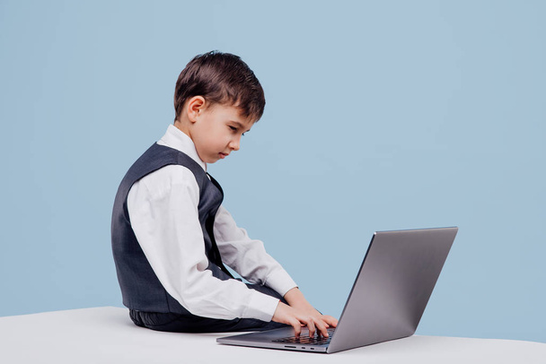 side view of curious little boy typing on laptop - Фото, изображение