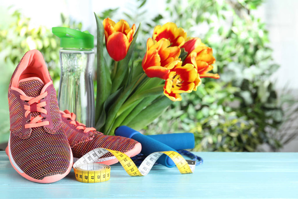 Koostumus kevään kukkia ja urheilu kohteita vaaleansininen puinen pöytä vastaan hämärtynyt vehreys
 - Valokuva, kuva