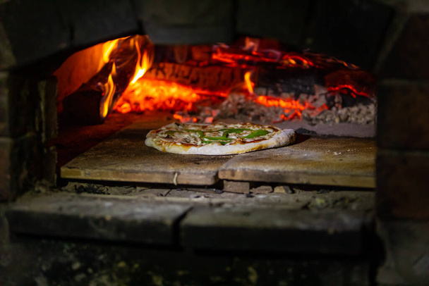Pizza cooks in wood fired campsite oven - Photo, Image
