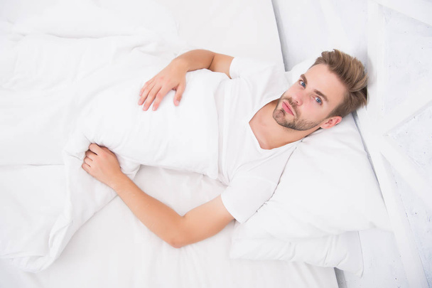 Causes of early morning headache. Migraine headaches. Sleep problems can lead to headaches in morning. Handsome man relaxing in bed. Snoring can increase risk headaches. Common symptom of sleep apnea - Фото, изображение