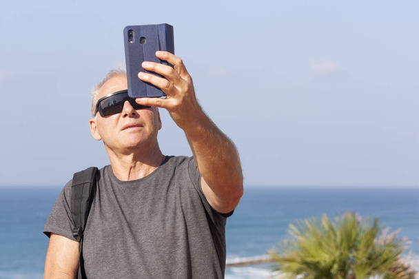 Tourist takes a selfie against the sea - Фото, изображение