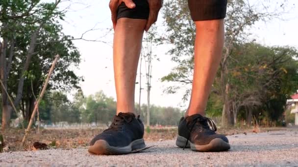 Азиатский старший мужчина держит руки на колене из-за боли в колене после пробежки в парке. Здравоохранение и медицина
. - Кадры, видео