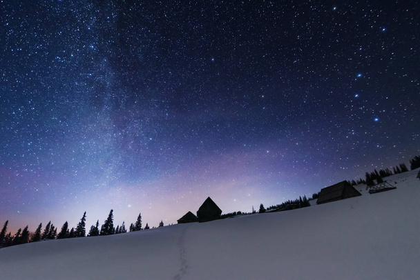 Una brillante noche estrellada en las montañas con la Vía Láctea en el cielo, Venus y millones de estrellas destacando hermosas cabañas de montaña en el valle
. - Foto, Imagen
