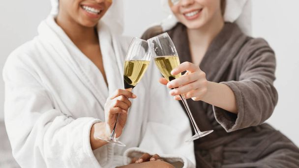 Обрезанные двумя многонациональными дамами, приветствующими бокалы шампанского
 - Фото, изображение