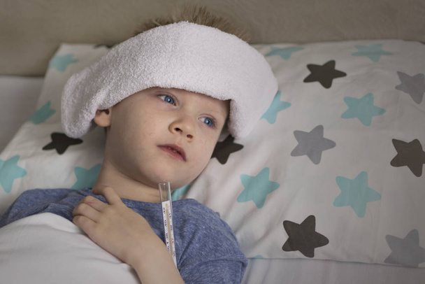 A criança triste doente em temperatura e dor de cabeça está na cama. Gripe constipações vírus da doença bacterium
 - Foto, Imagem