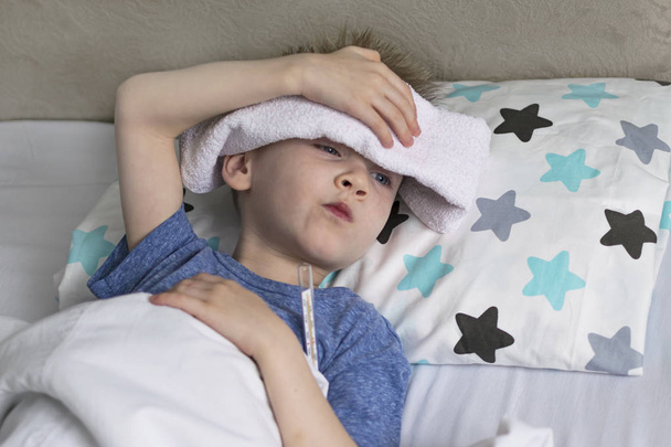 Krankes, trauriges Kind liegt bei Temperatur und Kopfschmerzen im Bett. Grippaler Erkältungsvirus - Foto, Bild