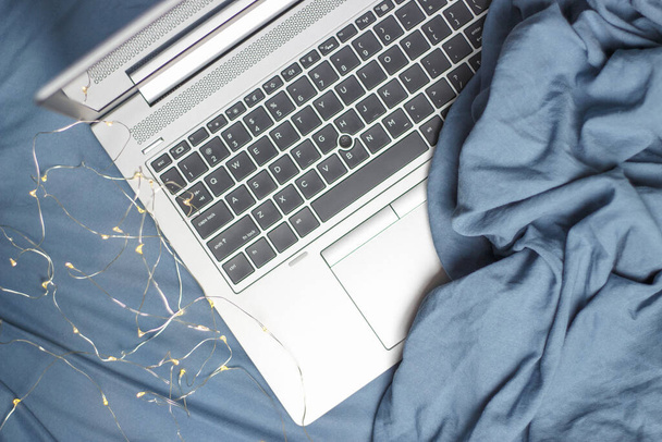 Laptop on a blue bed close up top view, a freelance concert. - Zdjęcie, obraz
