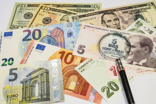 lähikuva Amerikan dollari, turkkilainen liira ja eurosetelit suurennuslasilla valkoisella pohjalla
 - Valokuva, kuva