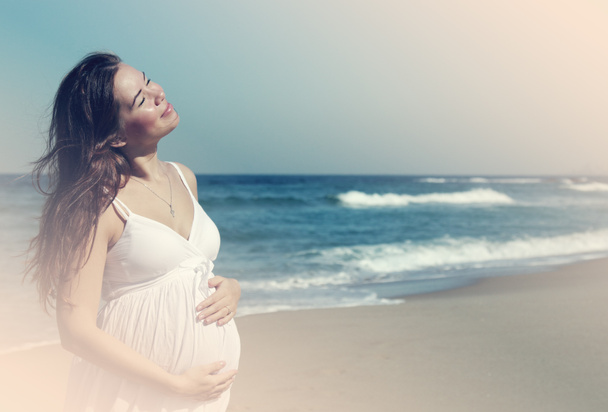 Красива вагітна жінка стоїть на пляжі
 - Фото, зображення