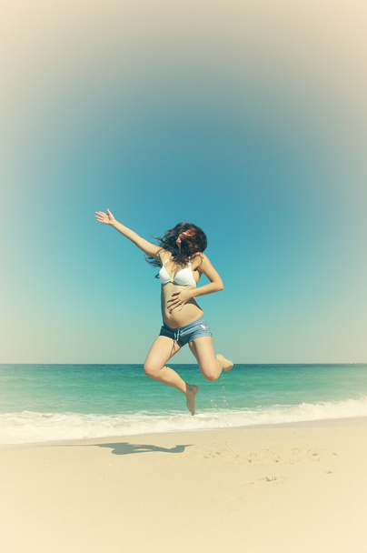 Красива вагітна жінка стрибає на пляжі
 - Фото, зображення