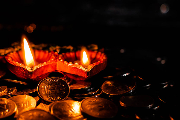 High angle shot of two glowing earthen lamps with coins against  - Foto, Imagem
