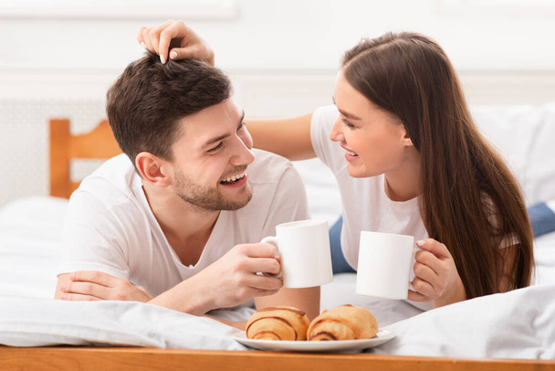 Радостная влюбленная пара, завтракающая в постели
 - Фото, изображение