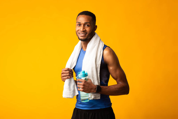 Afro deportista con toalla sosteniendo una botella de agua
 - Foto, Imagen