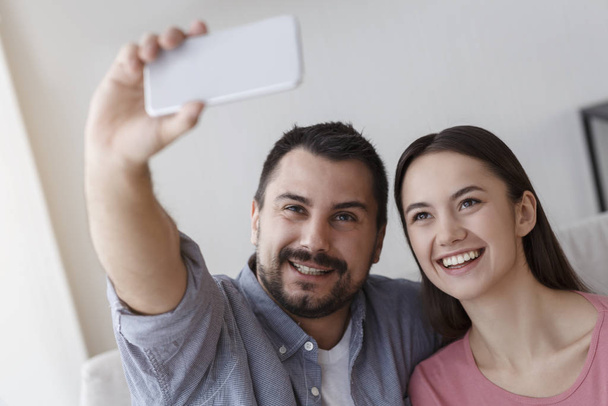 Girl and guy in love making selfie in living room - Foto, afbeelding