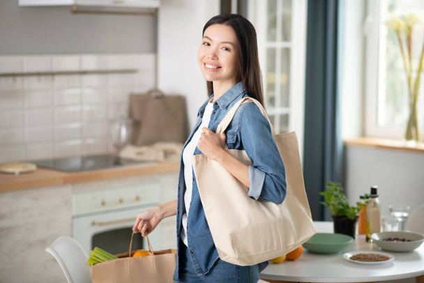 Smiling young woman with eco bags at home. - Photo, image