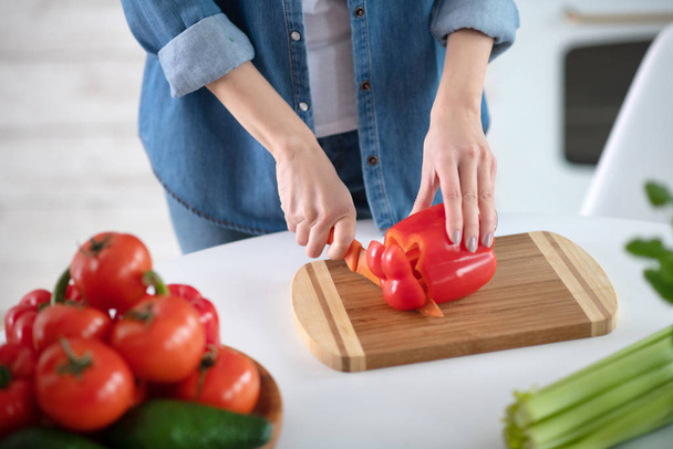 Female hands with knife cutting slice of red pepper. - Fotoğraf, Görsel