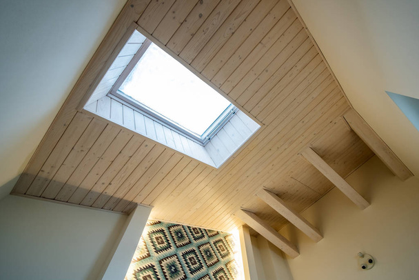 Techo de madera en una habitación mansarda contemporánea con ventana del ático ob superficie tablones decorativos
. - Foto, Imagen