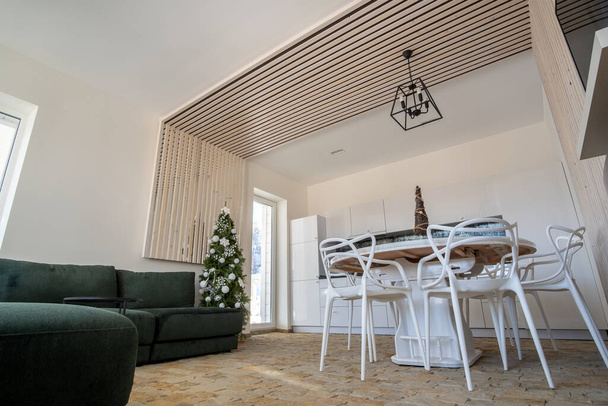 白い壁、装飾的な木製の要素、現代的な家具や大きな柔らかいソファ付きのモダンな広々としたキッチンのインテリア. - 写真・画像
