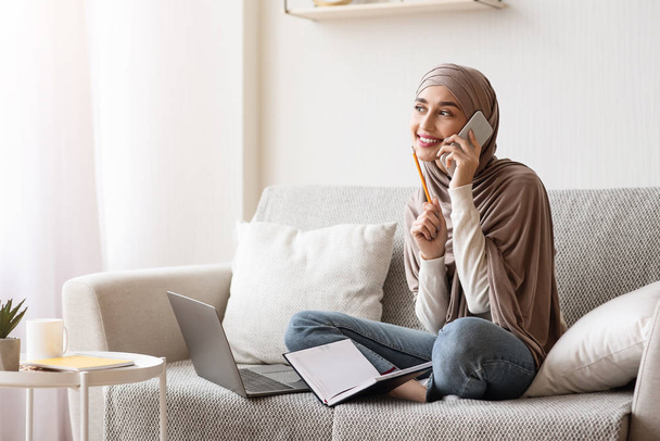 自宅で携帯電話で話すイスラム教徒の女の子,面接予約を作成します - 写真・画像