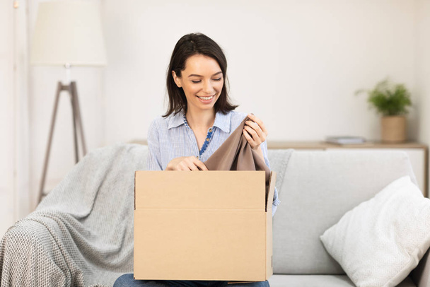 Smiling girl putting clothes in cardboard box - Photo, image