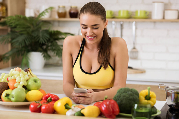 Healthy lifestyle. Woman texting on phone in kitchen - Фото, зображення