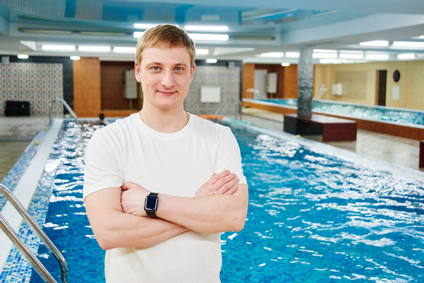 Athletic man professional swimming instructor stands and smiles on the background of the swimming pool in the gym - Foto, Imagem