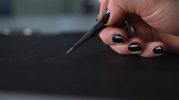 A lány fekete ceruzát rajzol fekete papírra. A tervező rajzol egy vázlatot. egy fekete ceruzával. Lányművész. Divattervező munka közben. - Felvétel, videó