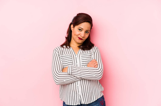 Middle age latin woman isolated on a pink background frowning face in displeasure, keeps arms folded. - Photo, Image