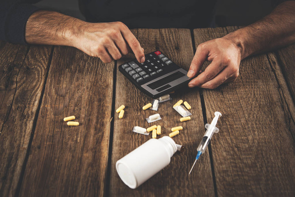 man hand  syringe with calculator and drug - Fotoğraf, Görsel