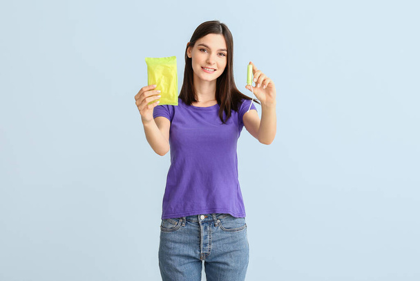 Jeune femme avec tampon et tampon menstruel sur fond clair
 - Photo, image