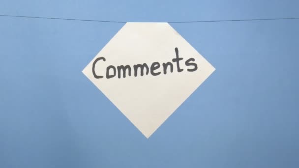 Queimando e fumando folha branca de papel com uma inscrição preta "comentários" em um fundo azul
 - Filmagem, Vídeo