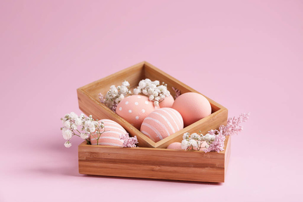 Cajas con hermosos huevos de Pascua y flores sobre fondo de color
 - Foto, imagen