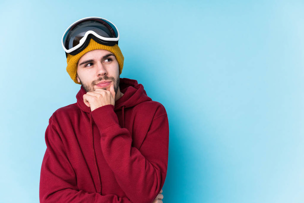 Jovem caucasiano vestindo uma roupa de esqui isolado olhando para os lados com expressão duvidosa e cética
. - Foto, Imagem