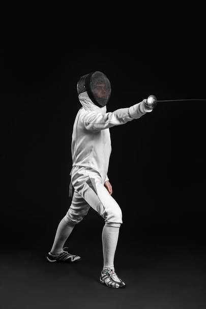 Young fencer on dark  background - 写真・画像