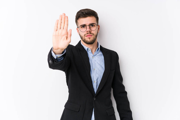Νεαρός καυκάσιος επιχειρηματίας ποζάρει σε λευκό φόντο απομονωμένος Νεαρός καυκάσιος επιχειρηματίας στέκεται με απλωμένο χέρι δείχνοντας στοπ, εμποδίζοντας σας. - Φωτογραφία, εικόνα