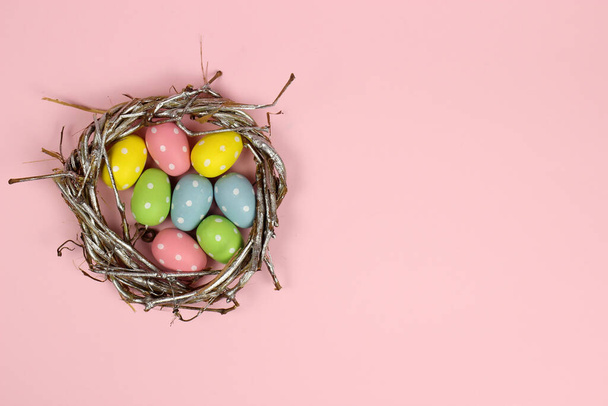 Huevo de Pascua colorido en un nido sobre un fondo rosa
 - Foto, Imagen