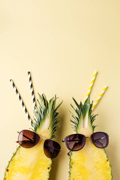 Fresh pineapple cut in two part, notebook or sketchbook and sunglasses on yellow background. Summer concept. Creative flat lay with copy space. Top view. - Фото, изображение